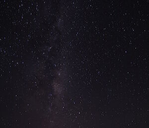 Very bottom of picture is Casey station with green store, casey sign and hags parked in a line, above for four 5ths of the picture is the night sky with the milky way and scattering of stars