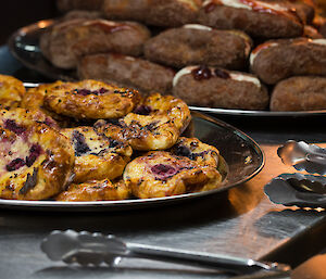 Trays of danish pastries and cream and jam filled donuts on buffet