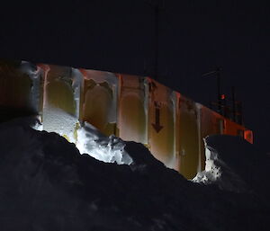 Side of a yellow building showing large bank of snow built up almost to the top of the building