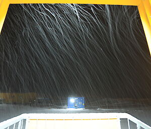 Looking out of the door at snow dumping down in the dark but lit up by light from inside