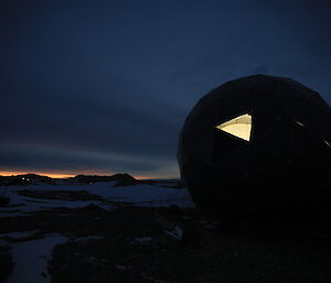 Night time view of the ANARESAT dome with one panel missing which allows the inside light to shine out