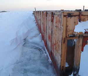 Side view of old wooden building that has ice coming halfway up the sides