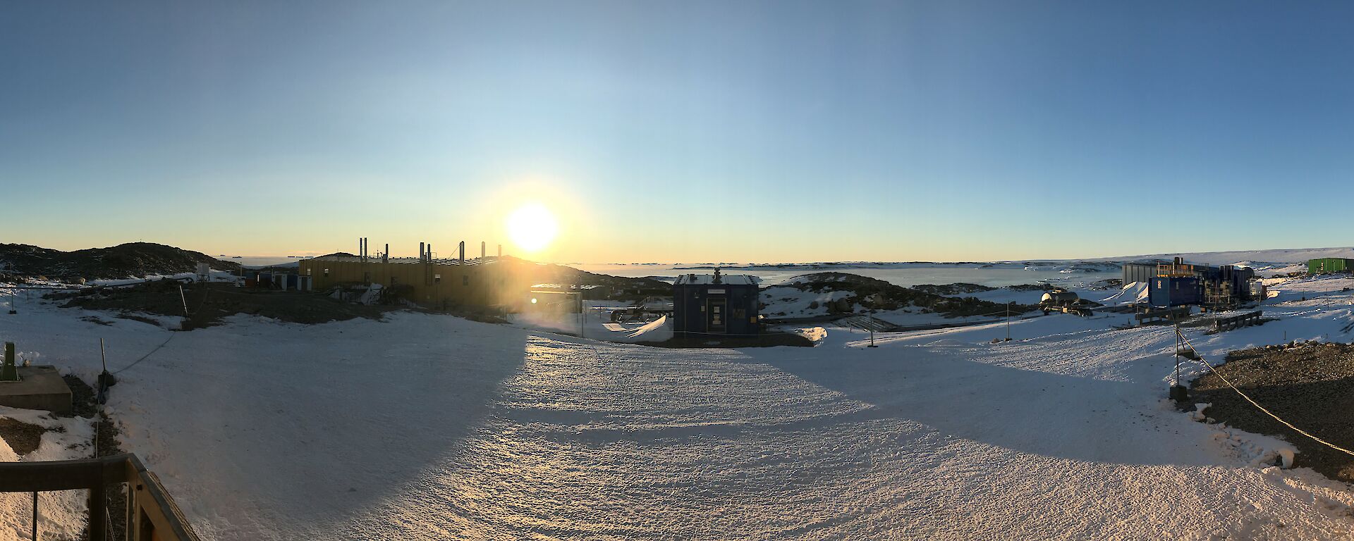 Panorama shot of Casey station from the Operations Building front deck, showing building, bay and blue skies
