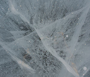 Close up of hard frozen ice with series of bubbles and cracks through it