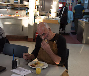 Man sitting at table eating breakfast with face covered in white and black makeup