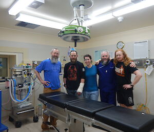 Group of 5 people standing behind operating table in operating theatre