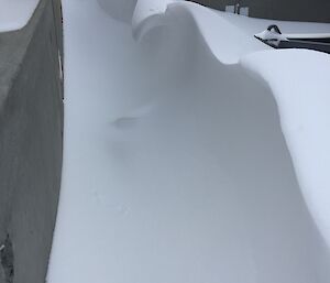 Bliz tail of snow around concrete structure create a shape like a breaking wave
