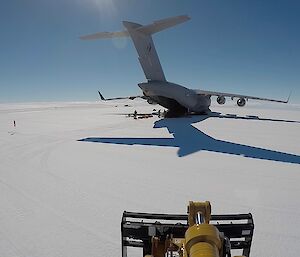 C-17 from rear with back ramp down and some stores on the ground around, on ice runway, with blue sky above