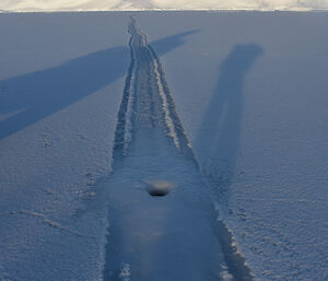 Air hole blown up through tide crack which extends from foreground off into the distance