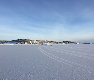 A group of people on quad bike in the distance across the flat expanse of sea-ice