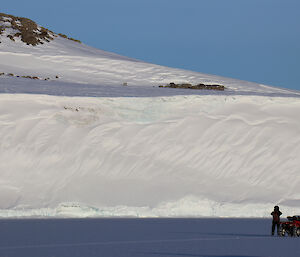 Quad bike and dismounted rider, dwarfed by ice cliffs