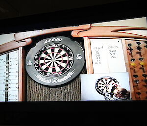 Image of tv screen showing darts board with score sheet either side