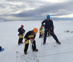 Two men drilling ice screws into side of icy slope