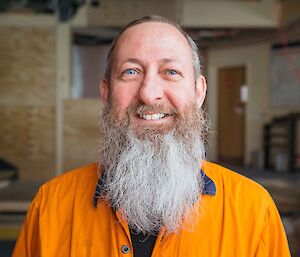 Headshot of man in hi-vis shirt smiling with long grey beard.