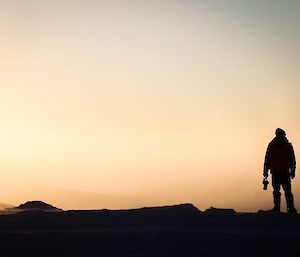 Man sillouetted against a foggy pale orange glow.