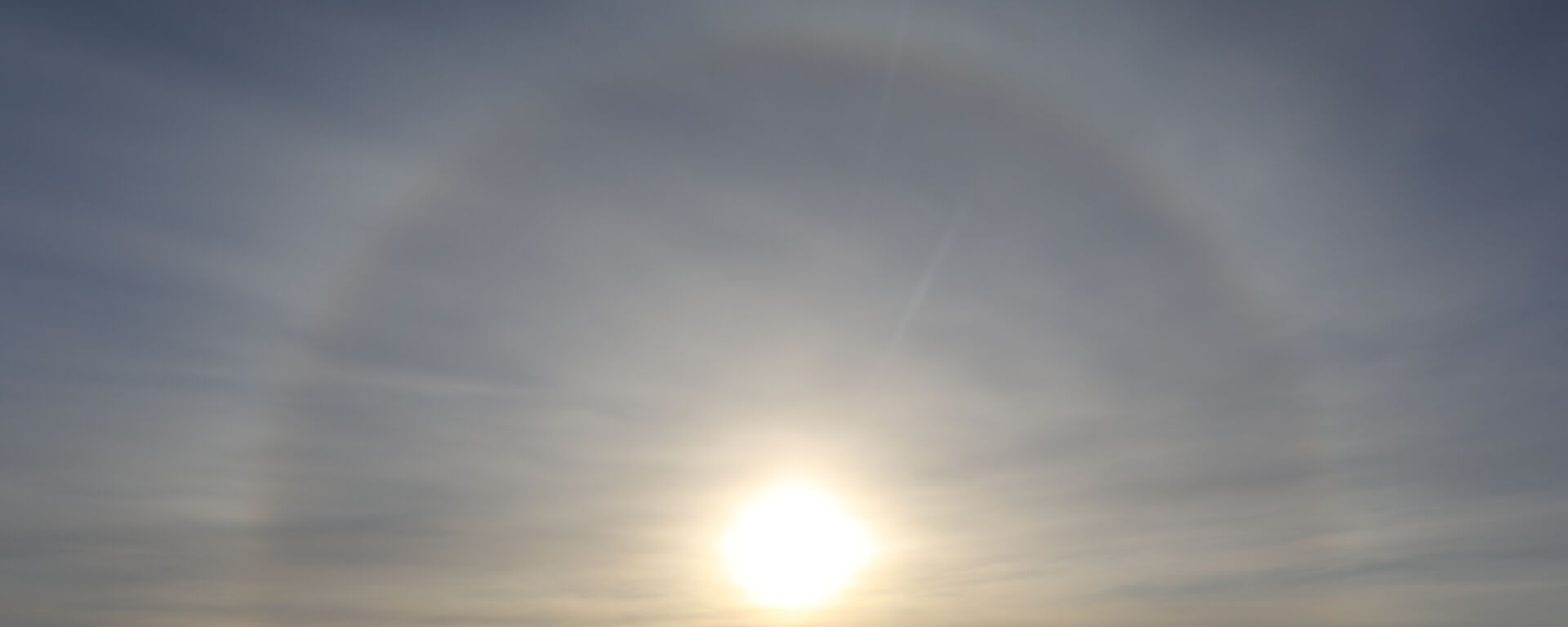 Photo taken directly into the sun showing a halo around the sun, foreground station buildings