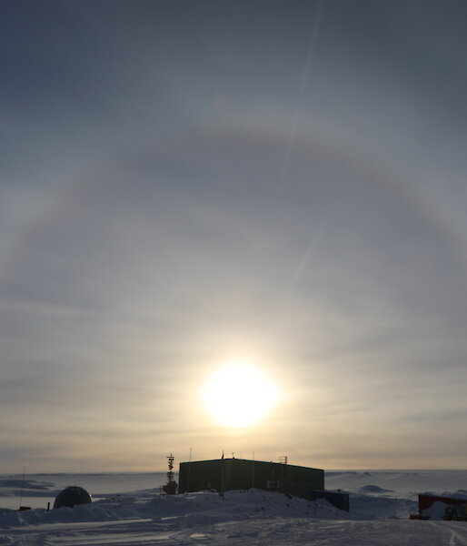 Photo taken directly into the sun showing a halo around the sun, foreground station buildings