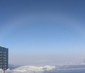 View across station buildings into fog over bay, above fog is a rainbow shape made of fog particles