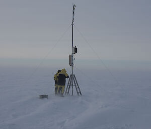 Two men standing at base of AWS tower in cold weather gear, white landscape with drifting snow