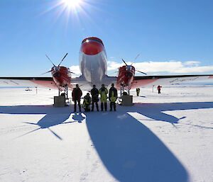 Five men standing under the nose of a Basler aircraft parked on an ice runway