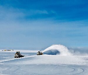 Ice runway with tractor and snow blower clearing. Big plume of snow in front of snow blower