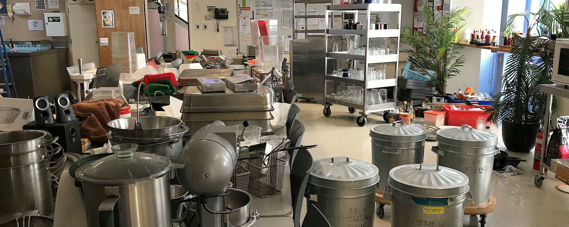 A long table in the mess covered to overflowing with kitchen equipment