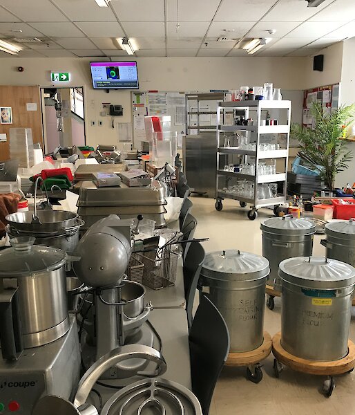 A long table in the mess covered to overflowing with kitchen equipment