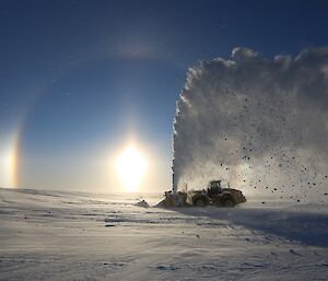 Sun Halo in sky, in foreground snow blower jetting snow into the air