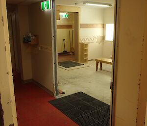 Corridor leading into empty room with patched walls and some hooks and benches