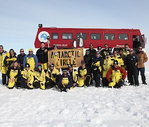 72nd ANARE Casey expeditioners at Antarctic Circle in front of red Terra bus