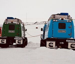 Blue and Green Hägglunds parked and plugged in waiting for their next job