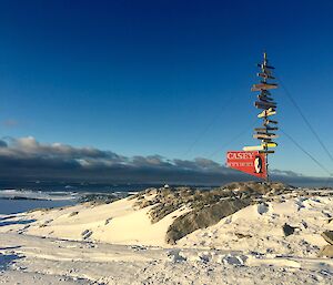 Sunset lighting on the Casey sign post with a background of Newcomb Bay and foreground of snow and rock