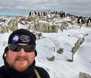 Andrew Frankham with penguins in background on top of rocks