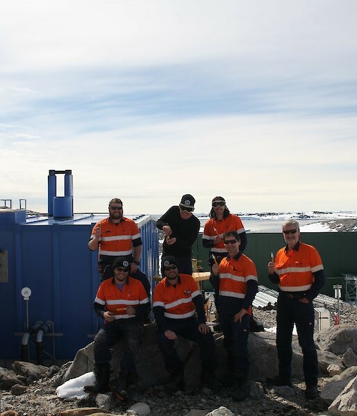 The electrical team standing near the Casey Emergency Power House (EPH, Blue building) with their “magic” test sticks and Newcomb Bay in the background.