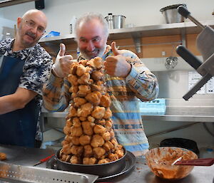 Expeditioners serving in the kitchen stand behind a huge tower of profiteroles