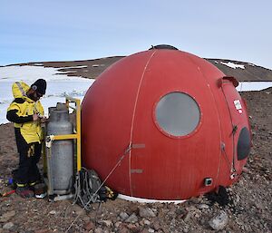 Expeditioner repairing gas fixture beside hut