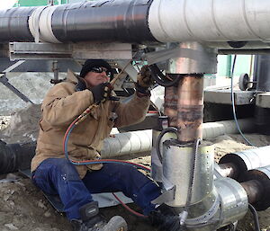 Tradesmen soldering in a tee on the pipe