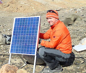 Expeditioner sitting beside a solar panel