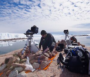 expeditioner working on camera equipment. Glacier in background