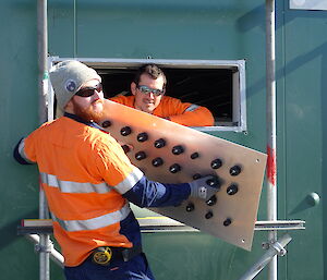 Tradesmen fitting a gland plate to the wall of a green building at Davis