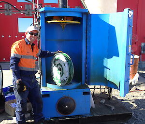 Expeditioner standing with a fuel drum crushed by the drum crusher