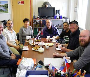 Group of Russian and Australian expeditioners having afternoon tea together around a table