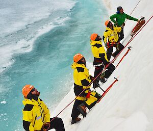 Expeditioners practicing ice climbing up a cliff