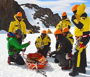 Expeditioners gathered around a stretcher receiving instruction from a field training officer