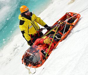 Expeditioners practicing stretcher lowers and hauls on an ice cliff