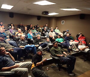 A theatre full of expeditioners staring towards a screen