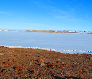 Red ‘apple’ huts in foreground, large frozen lake in background