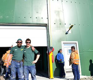 Two expeditioners in foreground, large green building in background