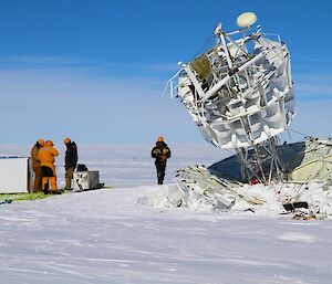 Expeditioners standing beside antenna structure preparing to dismantle instruments