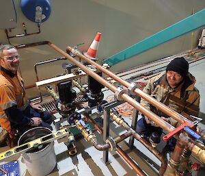 Two expeditioners installing heating pipes